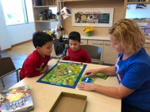 Two children and nurse play board game